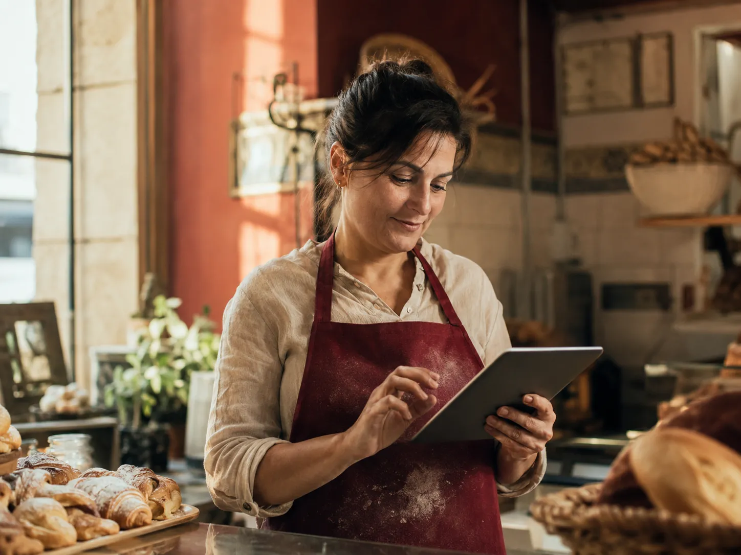 Una panadera consulta una tablet en su mostrador